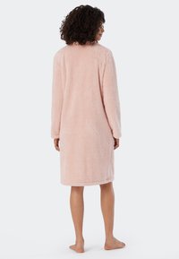 Rosa fluffig badrock med knälång design, långa ärmar och mjukt texturerat material, visad bakifrån med en rak fåll.