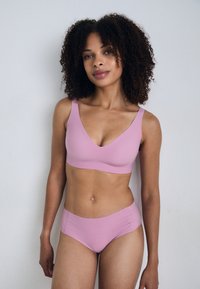 Roze, naadloze bh met een V-halsontwerp en brede schouderbanden, gecombineerd met bijpassende high-waisted panties. Zachte textuur, minimalistische stijl.