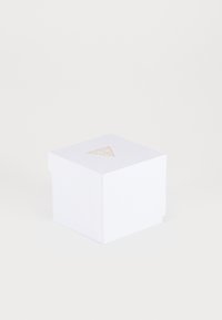 Hvid firkantet gaveæske med en tekstureret overflade, prydet med et guld trekantlogo på toppen, lukket med en fold-over flap.