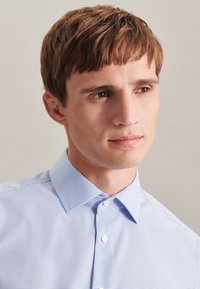 Lichtblauw geruit overhemd met een klassieke kraag en knoopsluiting, met een gladde katoenen textuur en subtiel ruitpatroon.