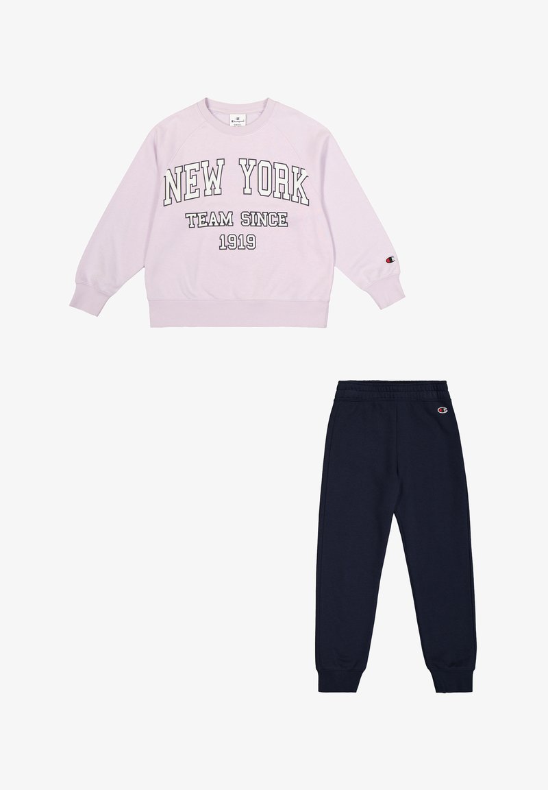 Sudadera lila con "NEW YORK TEAM SINCE 1919" en impresión negrita, combinada con joggers azul marino, que tienen una cinturilla y puños elásticos.