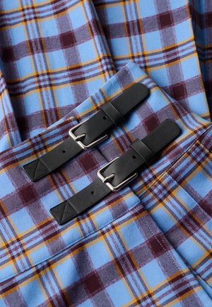 Geruit stof in blauw, bordeauxrood en geel. Twee zwarte leren riemen met zilveren gespen zijn duidelijk zichtbaar.