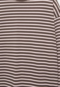 Tessuto a strisce orizzontali marroni e bianche con una texture morbida, mostrato come parte di un indumento a maniche lunghe.