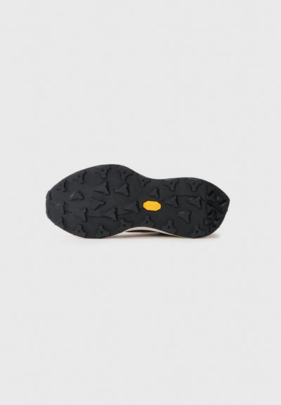 Talpă de cauciuc neagră cu crampoane multidirecționale și un logo galben Vibram în centrul său, izolată pe un fundal alb.