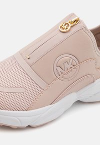 Light pink slip-on sneakers with mesh and synthetic materials, featuring a gold zipper, logo accent, and textured white sole.