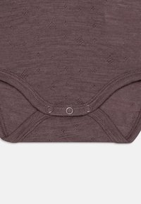 Body de infant cu un ton mauve închis, cu un model texturat, având închidere cu nasturi în partea de jos și o guleră rotundă. Țesătură moale și elastică.