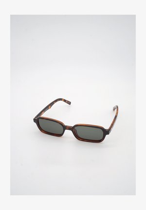 Ορθογώνια γυαλιά ηλίου με σχέδιο χελώνας και σκοτεινούς πράσινους φακούς, ακουμπισμένα σε λευκή επιφάνεια, στραμμένα ελαφρώς προς τα δεξιά.