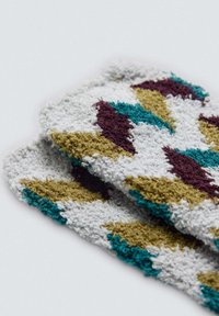 Tejido suave con un patrón de formas en azul verdoso, burdeos y dorado sobre un fondo blanco, con un acabado texturizado y suave.