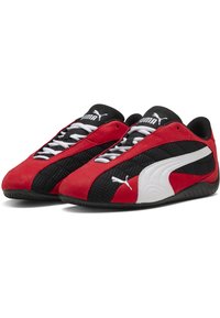 Zapatillas rojas y negras con un diseño de malla y acentos de ante, logo blanco y suela negra contrastante, exhibiendo una forma de perfil bajo.