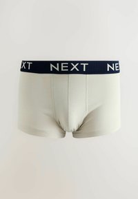 Herrboxershorts i ljusbeige bomull med midjeband i marinblått som har "NEXT"-logotypen i vitt. S jämmig textur, figurnära design och kort längd.