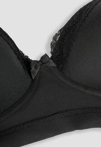 Sujetador negro acolchado con detalle de encaje, lazo de satén, material suave y bordes sin costuras. Vista en primer plano de los detalles de diseño y textura.