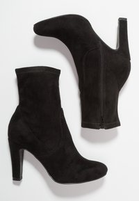 Bottes cheville en daim noir avec talons hauts, dotées d'une fermeture éclair latérale, d'une tige ajustée et d'un bout arrondi. Texture lisse et design sans coutures.