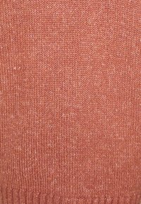 Knitted sweater in a warm rust color, featuring a soft texture with subtle variations and a ribbed hem at the bottom.