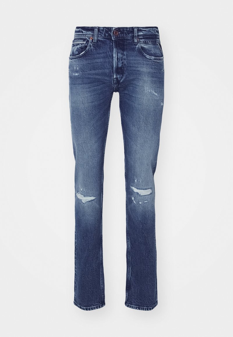 Donkerblauwe spijkerbroek met rechte pijpen, versleten plekken op de knieën, vijf zakken en een knoopsluiting bij de taille.