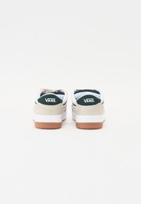 Vans tenisice imaju bijelu i bež gornjište, s tamnozelenim naglascima i logotipom, te potplatom od gume. Zaobljen oblik s mekanim oblogom.