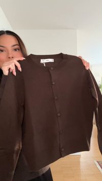 Cardigan marrone in materiale lavorato a maglia, caratterizzato da scollatura rotonda, maniche lunghe e sei bottoni sul davanti. Tessuto morbido.