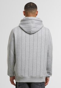 Felpa grigia con righe orizzontali, realizzata in un tessuto morbido. Presenta un cappuccio, maniche lunghe e un orlo a costine. Design semplice, stile versatile.