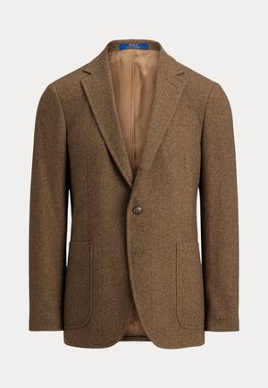 Καφέ μάλλινο σακάκι με σχέδιο ψαροκόκκαλο, δύο εμπρόσθιες πλαϊνές τσέπες, κλείσιμο με ένα κουμπί, γιακάδες με εγκοπή και μπεζ σατέν φόδρα.