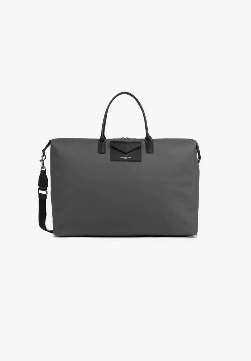 Sac de voyage en nylon gris avec des accents en cuir noir. Dispose de deux poignées supérieures et d'une bandoulière amovible, présentant un design minimaliste.
