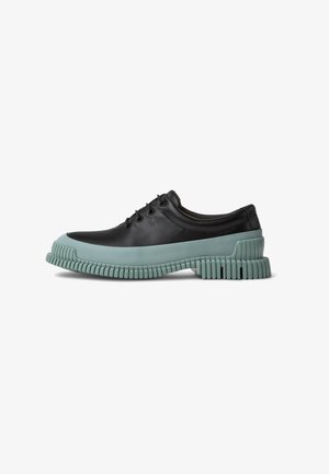 Scarpa di pelle nera con suola in gomma verde menta a contrasto. Presenta una punta arrotondata, sei fori per i lacci e una suola testurizzata per una migliore aderenza.