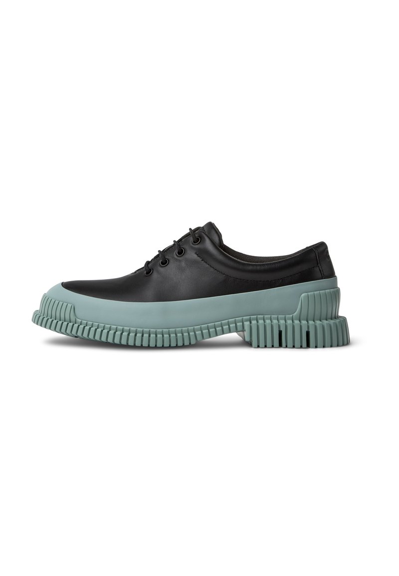 Zapato de cuero negro con una suela de goma verde menta en contraste. Presenta una puntera redondeada, seis ojales y una suela texturizada para mayor agarre.
