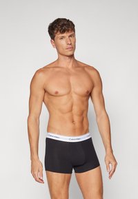 Čierne bavlnené boxerky s bielym opaskom s logom Calvin Klein. Spodná bielizeň má priliehajúci strih a hladkú textúru.
