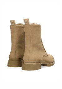 Stivali alla caviglia beige in pelle texturizzata con laccio frontale e zip laterale, dotati di suola spessa e due linguette per una facile indossabilità.