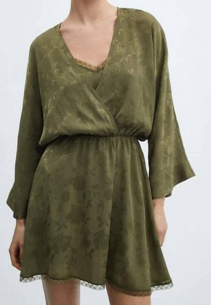 Oliwkowo zielona kwiatowa sukienka kopertowa z długimi rękawami, dekoltem w serek, elastyczną talią i koronkową lamówką przy dekolcie oraz na dole.