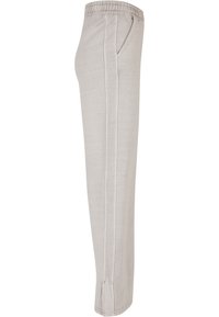 Lichtgrijze sweatpants van zachte stof, met een elastische tailleband, twee zijzakken en subtiele stiksels langs de zijkanten.