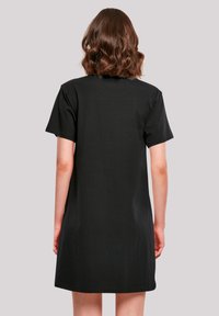 Schwarzes Kurzarmkleid mit lockerer Passform, aus weichem Baumwollstoff gefertigt. Der Rücken ist schlicht ohne Muster oder Verzierungen.