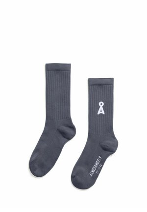 Paire de chaussettes courtes côtelées gris foncé avec un logo blanc près du haut et un texte blanc sur la semelle sur fond blanc.