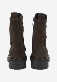 Bottines en daim marron avec une texture lisse, semelle en caoutchouc noire et fermetures éclair latérales pour un enfilage facile. Coutures renforcées le long des coutures.