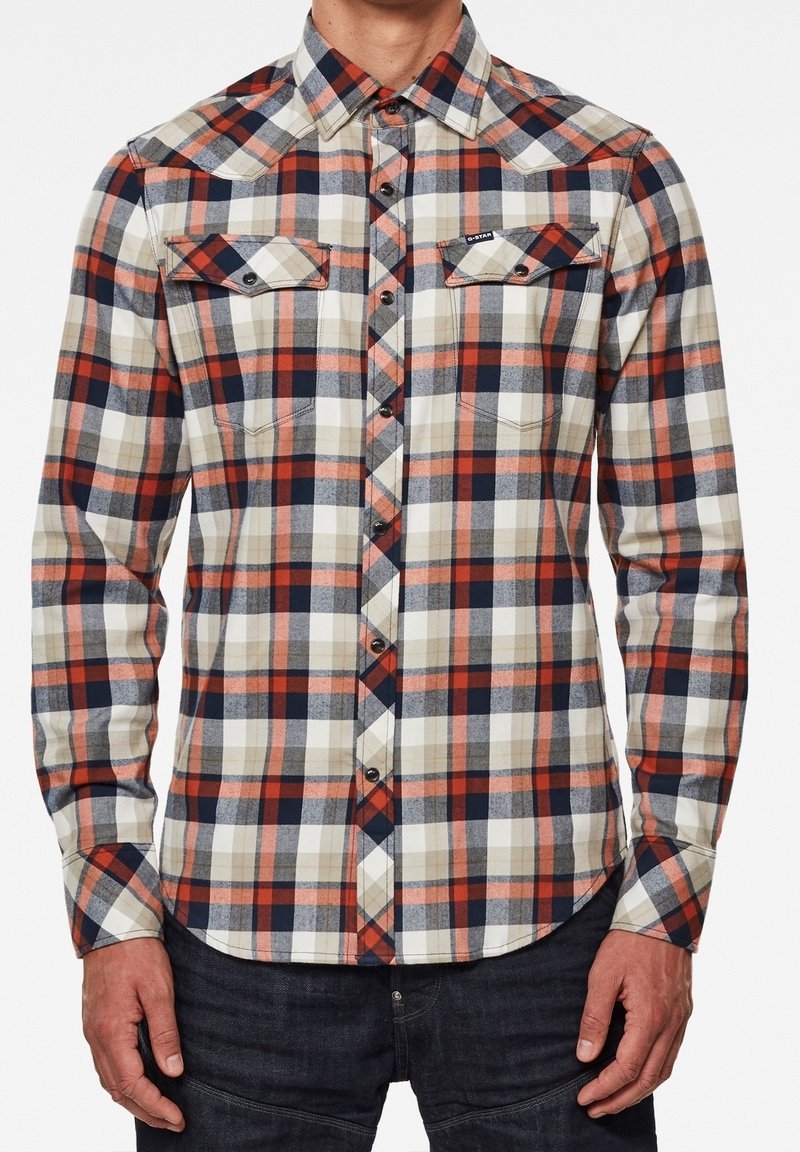 Skjorta med knappar i rutigt mönster som har marinblå, röd, beige och vit färg, med två bröstfickor och klassisk krage. Material av bomull.