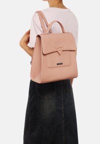 Zaino in pelle trapuntata rosa con una patta triangolare e hardware metallico. La borsa presenta una forma strutturata e spallacci regolabili.