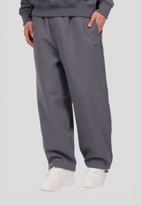 Szare spodnie dresowe wykonane z miękkiego materiału, o lu�źnym kroju, z bocznymi kieszeniami i subtelnym logo. W zestawie białe tenisówki.