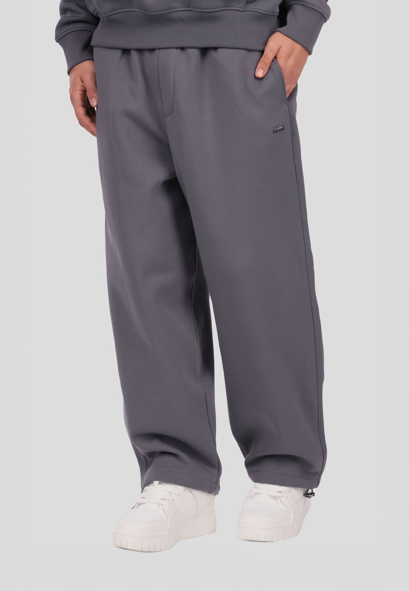 Szare spodnie dresowe wykonane z miękkiego materiału, o luźnym kroju, z bocznymi kieszeniami i subtelnym logo. W zestawie białe tenisówki.