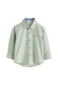 Camicia verde chiaro in cotone con colletto, maniche lunghe e piccolo ricamo di un orso sul petto. Bottoni in legno visibili.