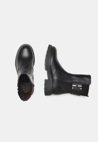 Black leather ankle boots with a sleek design, elastic side panels, chunkier soles, and metallic accents. Flat sole for stability and comfort.