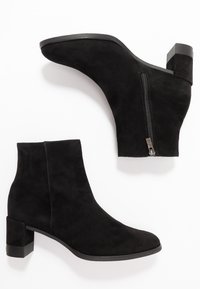 Bottines en daim noir avec une texture lisse, un talon carré et un zip sur le côté, présentant un design à bout arrondi élégant.