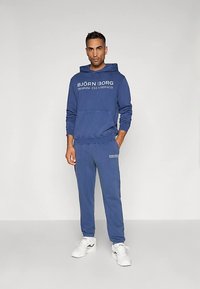 Blue hoodie and matching sweatpants set with front pocket and printed logo. Made of soft fabric; features ribbed cuffs and waistband.