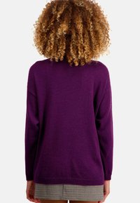 Pull en maille violet à manches longues, col rond et coupe ample, avec une texture douce et un ourlet côtelé.