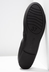 Musta kenkä, jossa on teksturoitu kumipohja ja kokoa 37 oleva merkintä. Sileä päällismateriaali, jossa on hillittyjä tikkauskoristeita.