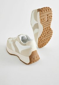 Sportowe sneakersy z miękkiej beżowej i białej siateczki z akcentami z zamszu, teksturowaną gumową podeszwą i wyściełanym kołnierzem dla wygody.