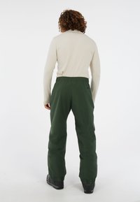 Groene, geïsoleerde sneeuwbroek met een relaxte pasvorm. Elastische tailleband, stevig materiaal en verstevigde boorden, geschikt voor buitenactiviteiten.