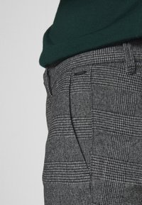 Grijze geruite broek met een gestructureerde stof, voorzien van een getailleerde pasvorm, zijzakken en een platte voorkant.