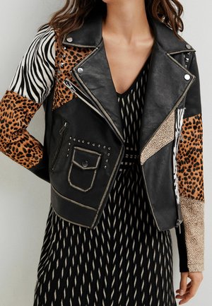 Veste de moto en cuir noir avec des panneaux imprimés animaliers, des studs en argent, et des manches contrastées avec des motifs zèbres et léopards.