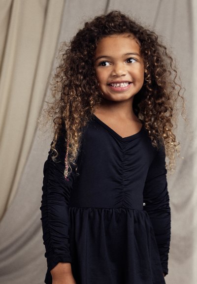 Μαύρο φόρεμα με μακριά μανίκια, πτυχώσεις στο μπροστινό μέρος και συγκεντρωμένη φούστα. Διαθέτει υφαντό ύφασμα και μικρό λογότυπο στο στρίφωμα.