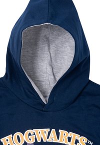 Felpa blu navy con fodera interna grigia sul cappuccio, caratterizzata da un logo giallo "HOGWARTS" sul petto. Tessuto morbido, vestibilità standard.