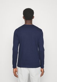 T-shirt a maniche lunghe blu navy realizzata in tessuto morbido, con scollo rotondo e vestibilità comoda. Texture liscia senza motivi o dettagli visibili.