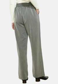 Pilkos juostelės kelnės su laisvu siluetu, elastinga juosmens juosta ir šoninėmis kišenėmis. Audinys turi lygią tekstūrą, akcentuojančią vertikalias linijas.